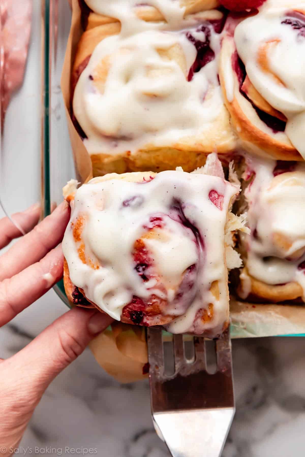 hand and spatula pulling a sweet roll out of the pan.