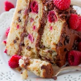 slice of raspberry chocolate chip layer cake on a white plate with a fork