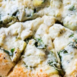 sliced spinach artichoke pizza on a pizza pan