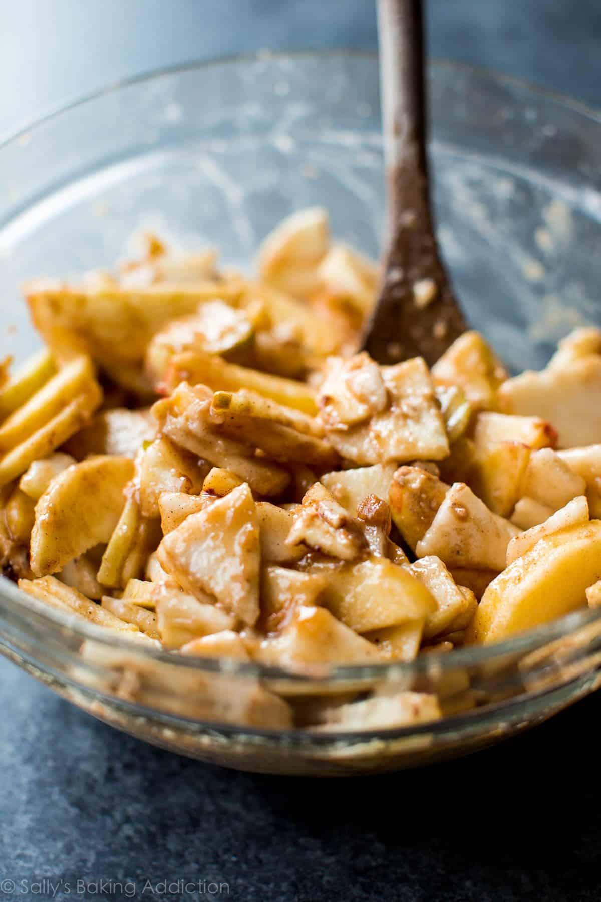 apple and pear crisp filling in a glass bowl with a wood spoon