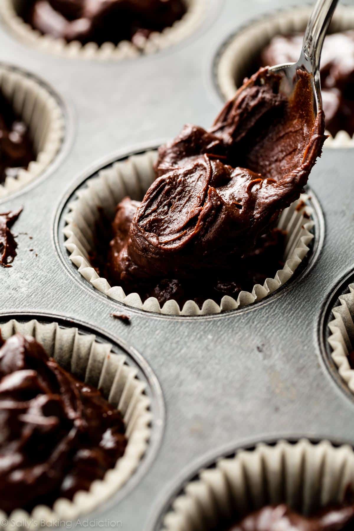 spooning muffin batter into a muffin pan