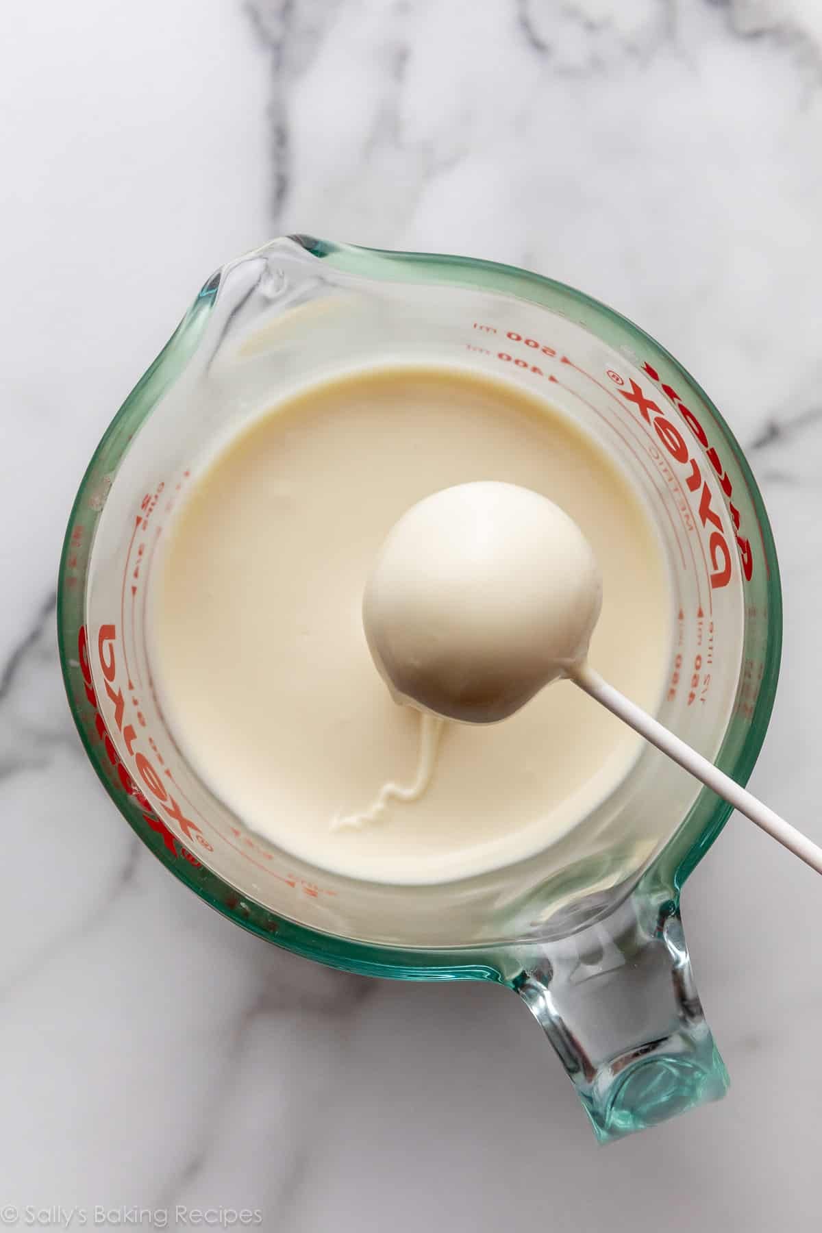 cake ball on lollipop stick coating in white chocolate.