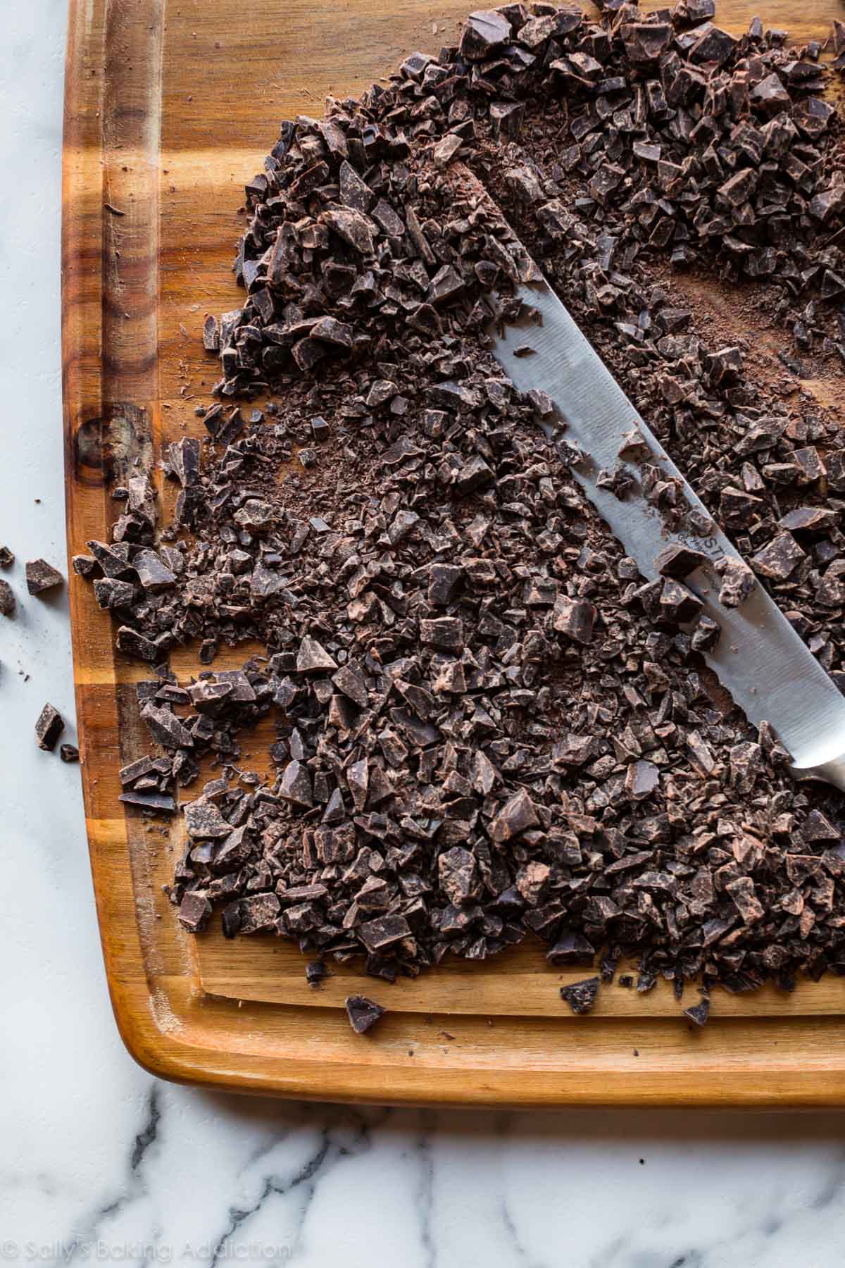 Chopped chocolate on a wood cutting board for truffles
