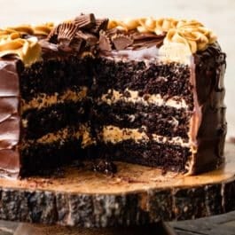 3 layer chocolate cake with peanut butter frosting and dark chocolate ganache on wood cake stand.