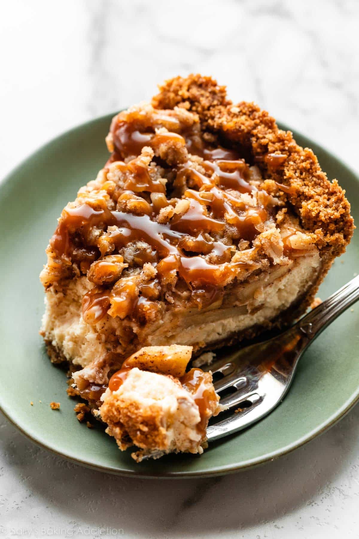 up close photo of caramel apple cheesecake pie slice on green plate.
