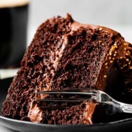 slice of Guinness chocolate cake on black plate with fork going through it.