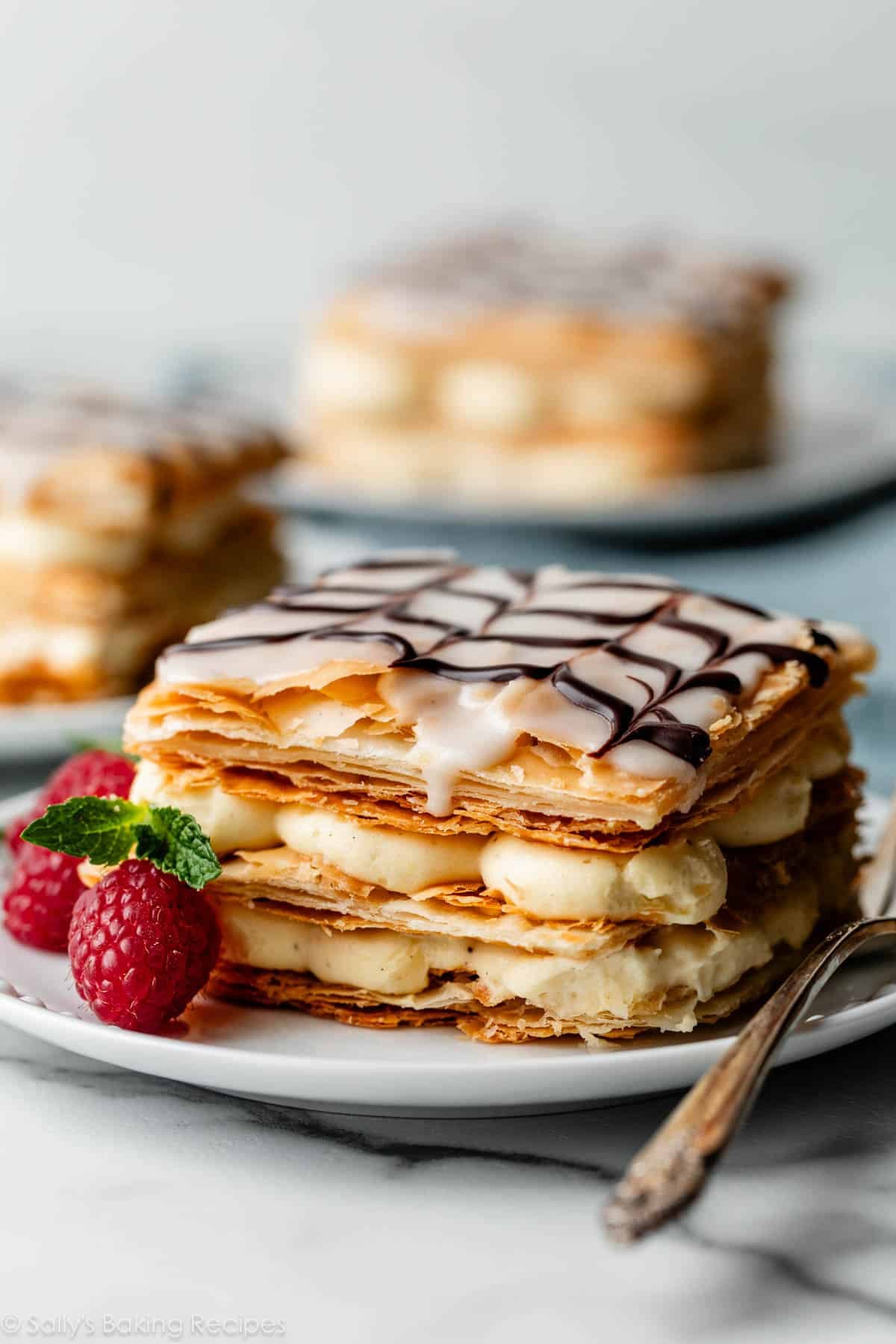 mille-feuille square serving on white plate with fresh raspberries.