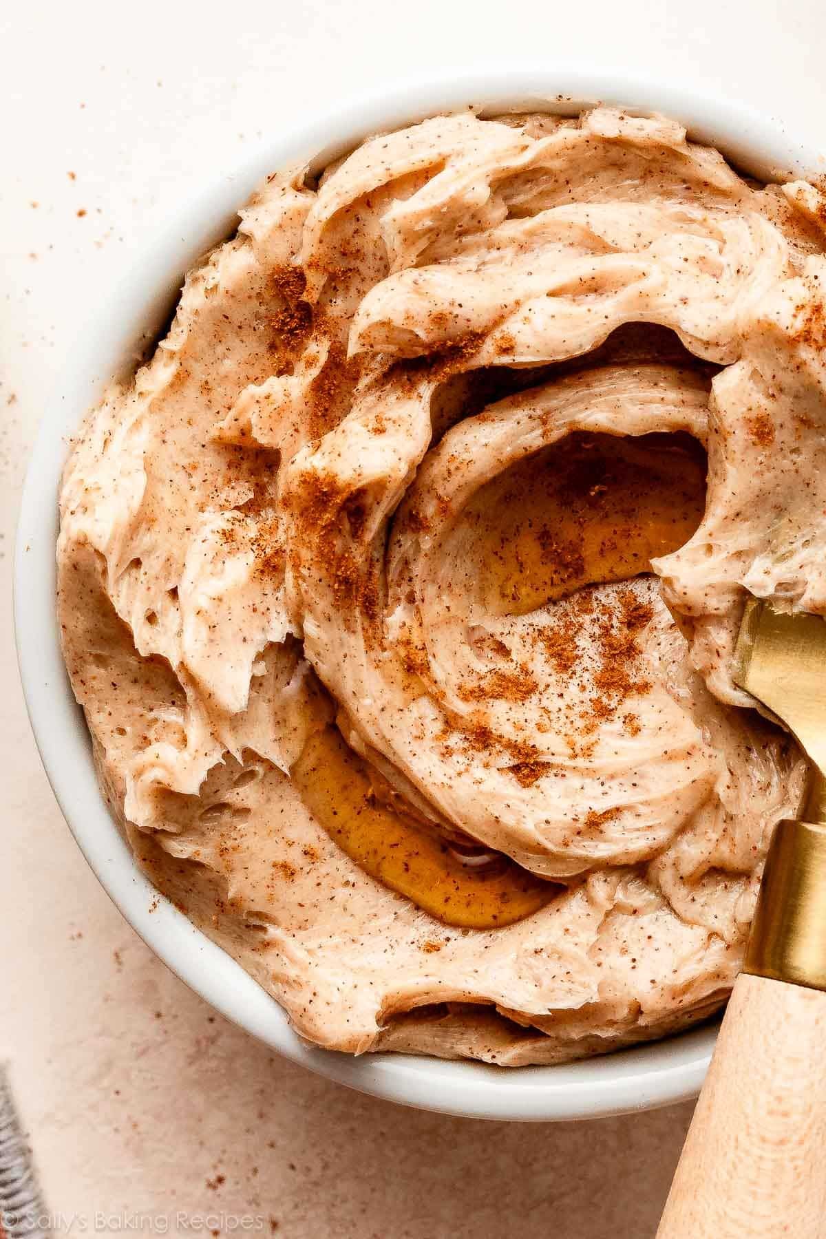 close-up of cinnamon butter in white dish with maple syrup drizzle on top.